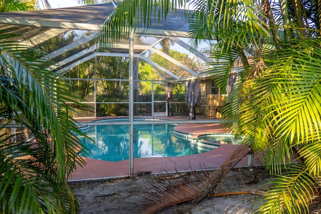 view of pool featuring glass enclosure and a pool with connected hot tub