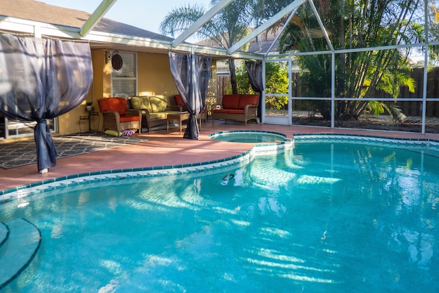 view of swimming pool featuring a lanai, a pool with connected hot tub, an outdoor hangout area, and a patio