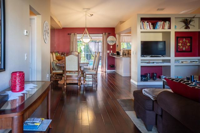 dining room with built in shelves, dark wood-type flooring, visible vents, and baseboards