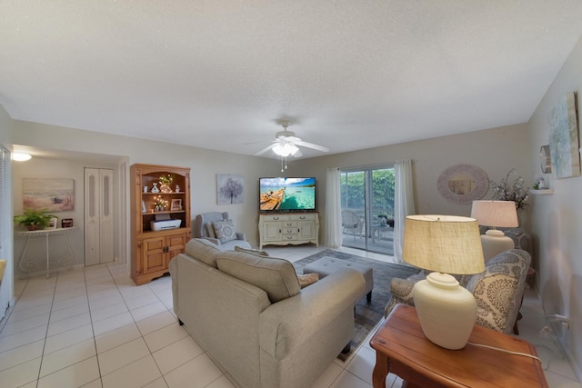 living room with a ceiling fan, a textured ceiling, and light tile patterned floors