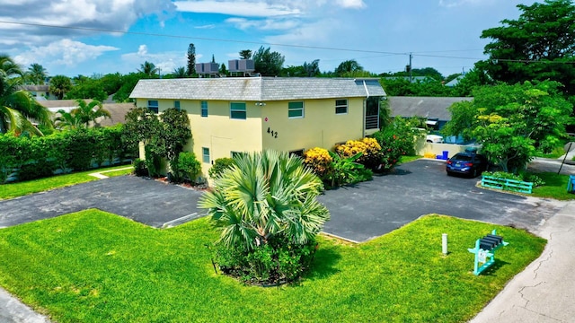 view of side of home with central air condition unit, stucco siding, aphalt driveway, and a yard