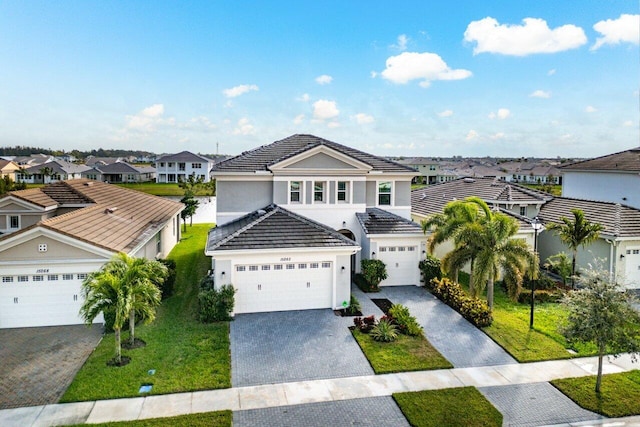 traditional home featuring a garage, a residential view, decorative driveway, and a tiled roof