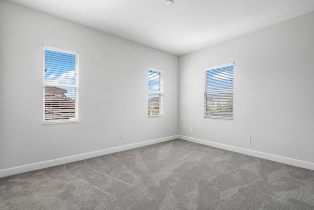 unfurnished room with carpet flooring, a textured ceiling, and baseboards