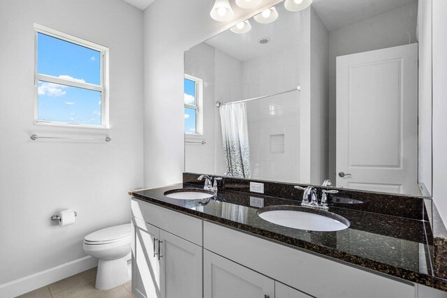 15262 Goldfinch Cir, Westlake, FL 33470 - bathroom with toilet, tiled shower, baseboards, tile patterned flooring, and double vanity