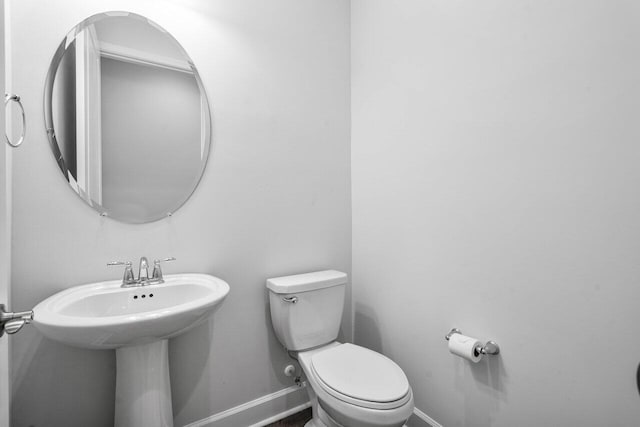 half bath featuring toilet and baseboards