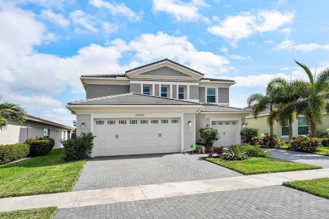 traditional-style home with a front lawn, decorative driveway, a tile roof, and stucco siding