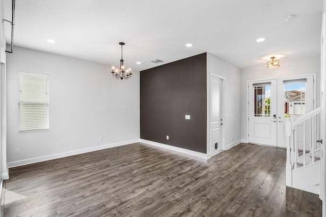 interior space featuring dark wood-style flooring, french doors, visible vents, a chandelier, and baseboards