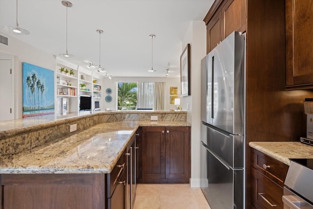 kitchen with light tile patterned floors, light stone counters, open floor plan, hanging light fixtures, and freestanding refrigerator