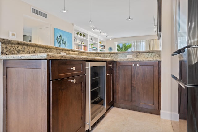 kitchen with light stone counters, wine cooler, freestanding refrigerator, and visible vents