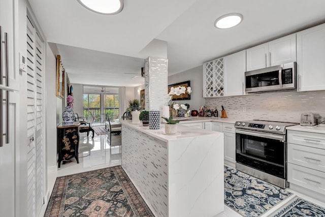 kitchen with stainless steel appliances, backsplash, white cabinetry, and a peninsula