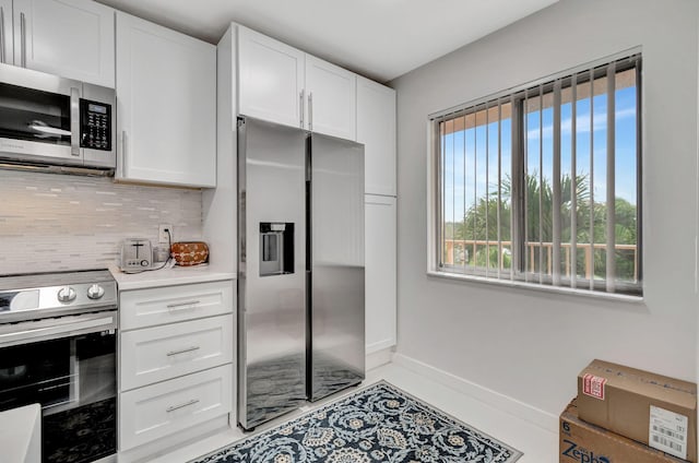 kitchen featuring stainless steel appliances, baseboards, white cabinets, light countertops, and backsplash