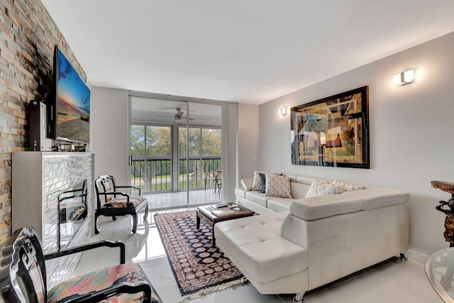 living area featuring expansive windows, a glass covered fireplace, ceiling fan, and baseboards