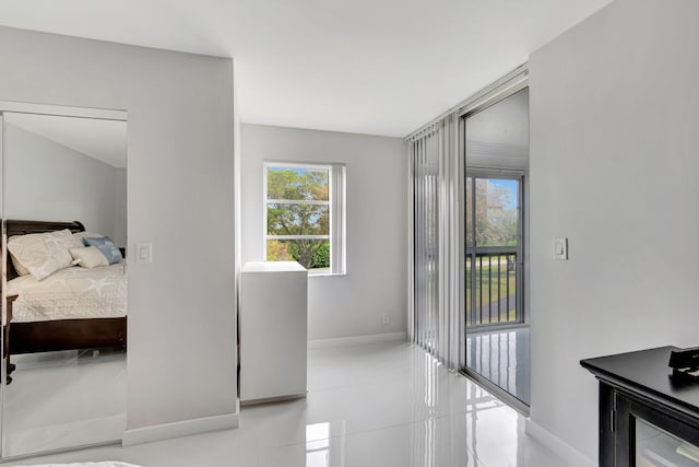 bedroom featuring light tile patterned floors, access to outside, multiple windows, and baseboards