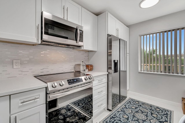 kitchen with tasteful backsplash, baseboards, stainless steel appliances, light countertops, and white cabinetry