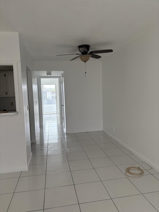 unfurnished room with light tile patterned flooring, a ceiling fan, and baseboards