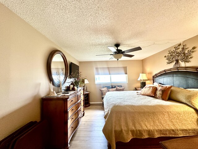 bedroom featuring a ceiling fan, a textured ceiling, baseboards, and wood finished floors