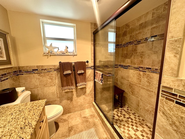 full bath featuring a wainscoted wall, tile walls, toilet, a stall shower, and vanity