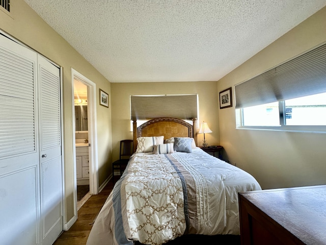 bedroom with dark wood-style flooring, a closet, a textured ceiling, ensuite bath, and baseboards