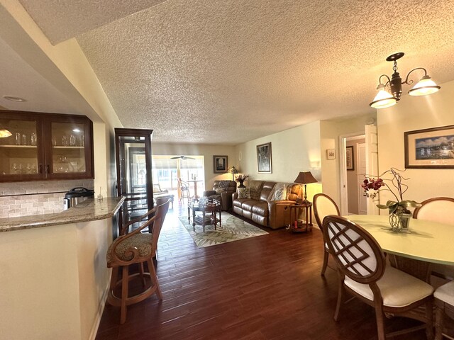 kitchen with light stone counters, dark wood-style flooring, glass insert cabinets, white appliances, and a peninsula