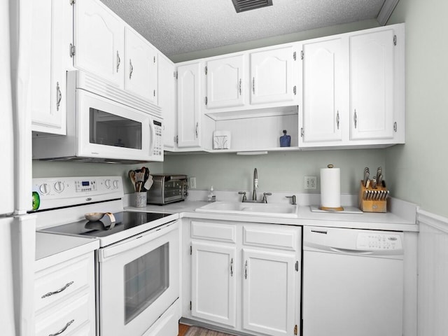 kitchen with light countertops, white cabinets, white appliances, a textured ceiling, and a sink