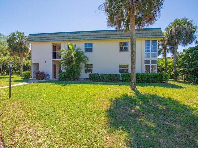 view of front of property with a balcony, stucco siding, and a front yard