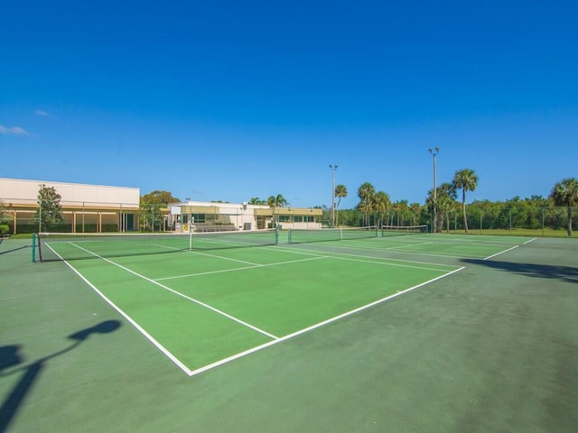 view of tennis court featuring community basketball court and fence