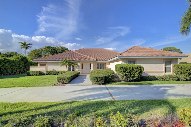 view of front of home featuring a tile roof, a front lawn, and stucco siding