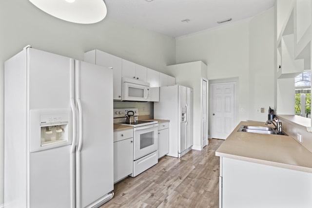 kitchen with white appliances, a high ceiling, a sink, white cabinets, and light countertops