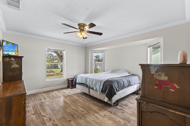 bedroom featuring visible vents, crown molding, a textured ceiling, and light wood finished floors