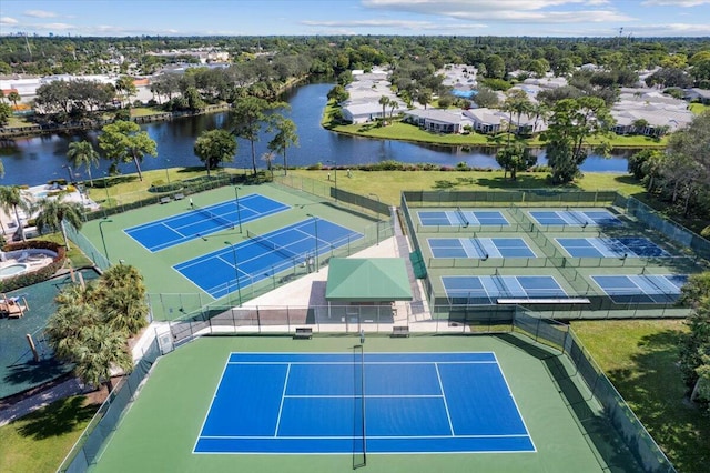 view of tennis court featuring a water view and fence