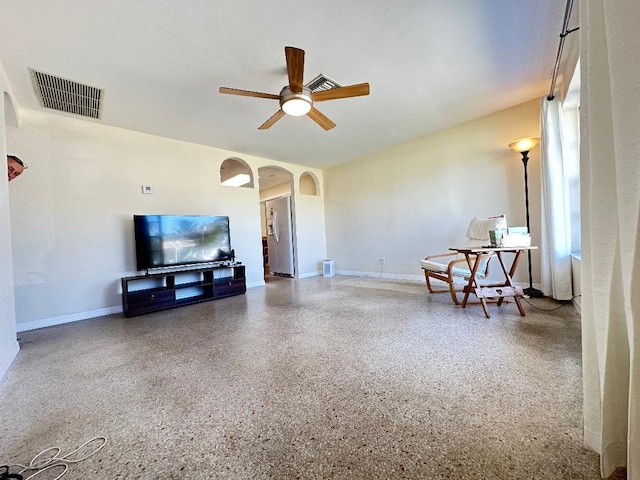 living room featuring visible vents, arched walkways, a ceiling fan, and speckled floor