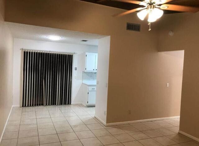 spare room with light tile patterned floors, a ceiling fan, visible vents, and baseboards