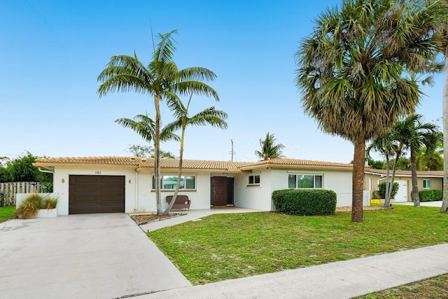 ranch-style house featuring an attached garage, stucco siding, driveway, and a front yard