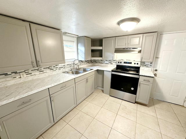 kitchen featuring under cabinet range hood, a sink, stainless steel range with electric cooktop, gray cabinets, and tasteful backsplash