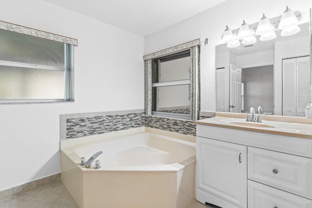 full bathroom featuring a closet, vanity, a bath, baseboards, and tile patterned floors