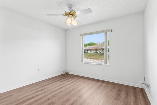 empty room with a textured ceiling, ceiling fan, light wood finished floors, and baseboards