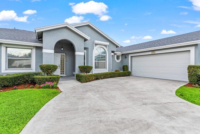 ranch-style house with driveway, a front lawn, an attached garage, and stucco siding