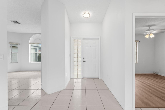 entrance foyer with a ceiling fan, visible vents, a textured ceiling, and light tile patterned floors