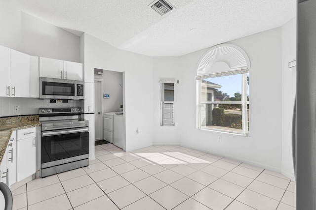 kitchen with visible vents, decorative backsplash, washing machine and clothes dryer, stainless steel appliances, and white cabinetry