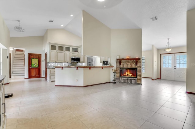 unfurnished living room featuring high vaulted ceiling, light tile patterned flooring, visible vents, french doors, and stairway