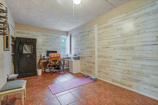 office area featuring a textured ceiling, tile patterned flooring, and wooden walls