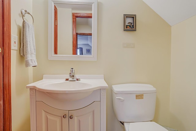 half bath with toilet, lofted ceiling, and vanity