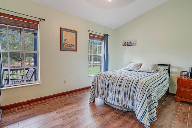 bedroom featuring lofted ceiling, dark wood-type flooring, and baseboards