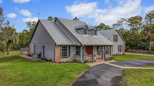 view of front of home featuring a porch, a front lawn, brick siding, and stucco siding