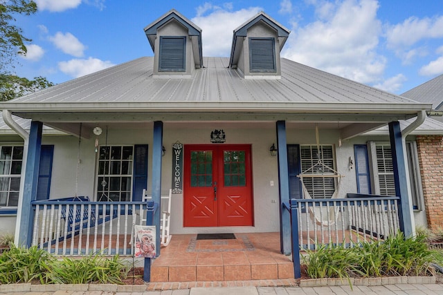 view of front of house featuring a porch, metal roof, and stucco siding