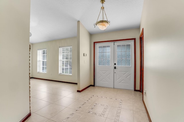 foyer entrance featuring french doors, light tile patterned flooring, a textured ceiling, and baseboards