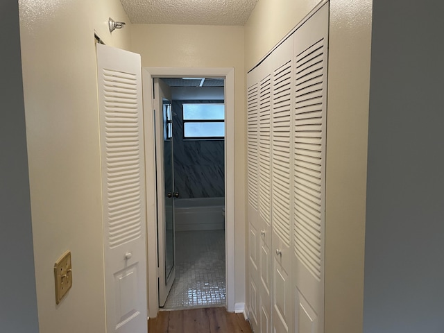 hallway featuring light wood-style floors and a textured ceiling