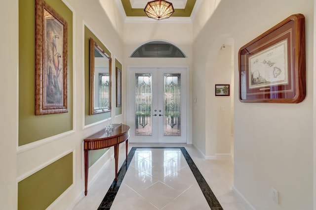 foyer entrance featuring ornamental molding, french doors, a high ceiling, and baseboards