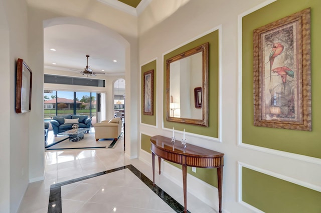 corridor featuring arched walkways, recessed lighting, baseboards, ornamental molding, and tile patterned floors