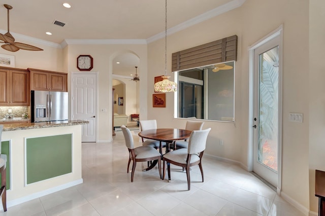 dining space with baseboards, crown molding, arched walkways, and a ceiling fan